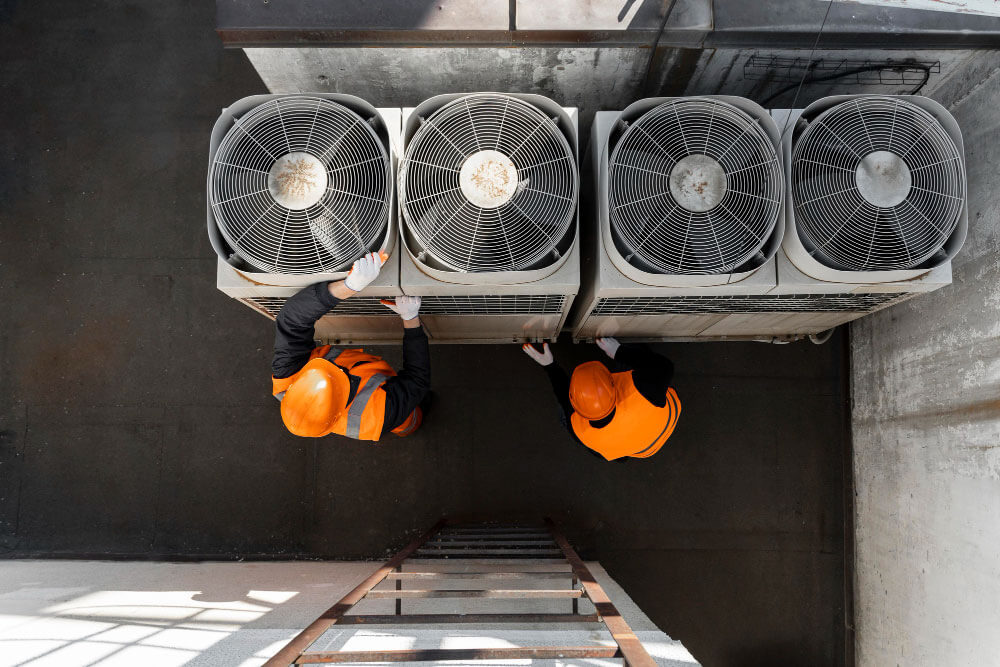 Two workers repairing commercial AC units